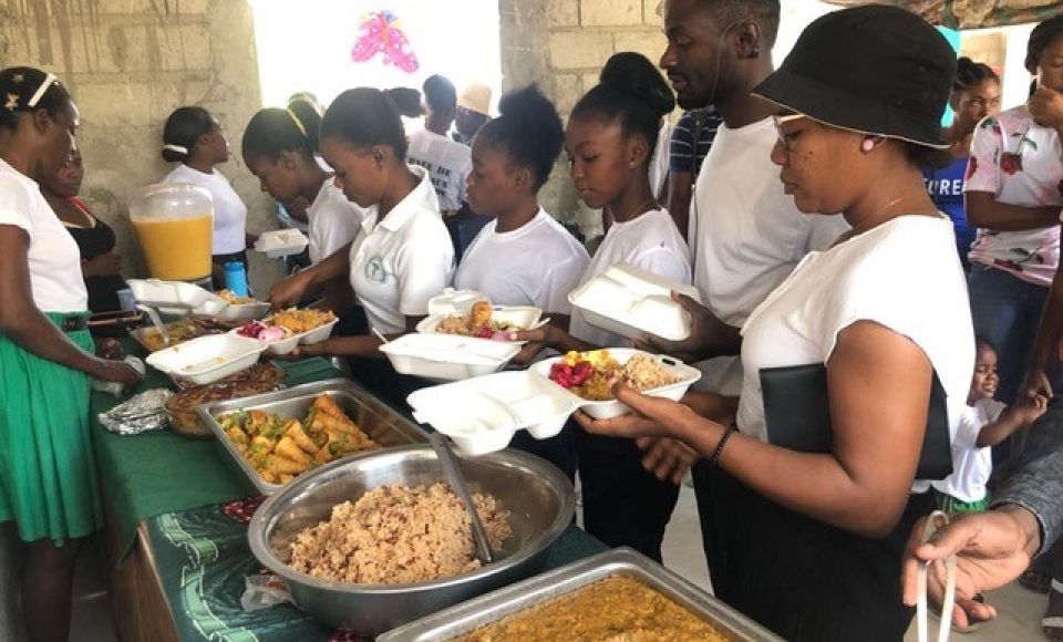 A group of people lining up for food at a canteen