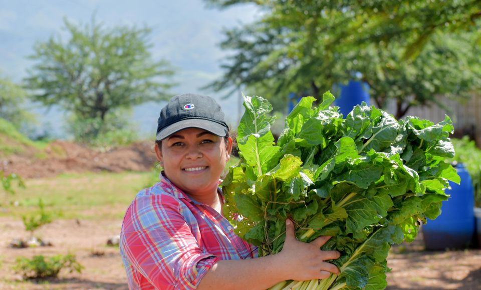 A woman holding crops smiling at the camera