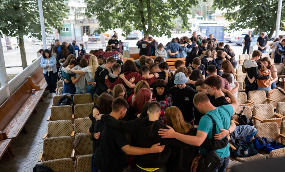 A group of young people, embracing each other in a circle.